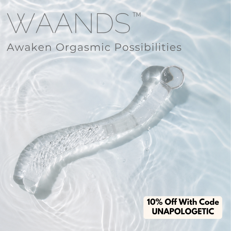 A glass cervix wand with a curved textured handle and bulbous end from Waands Crystal Pleasure Tools, sitting in water, with a discount code of "UNAPOLOGETIC" for 10% off