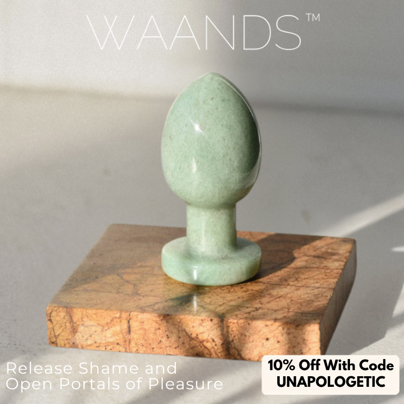 Green Aventuring butt plug with an egg shape, and small stem with a flat end sitting on a wood coaster with a coupon code for 10% off Waands Crystal Pleasure Tools with code UNAPOLOGETIC